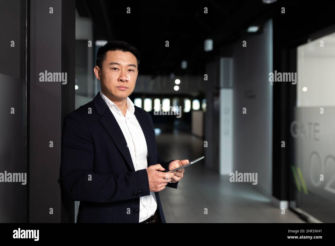 Serio lavoratore maschile asiatico si è concentrato sul lavoro di lavoro con computer tablet in un ufficio moderno Foto Stock