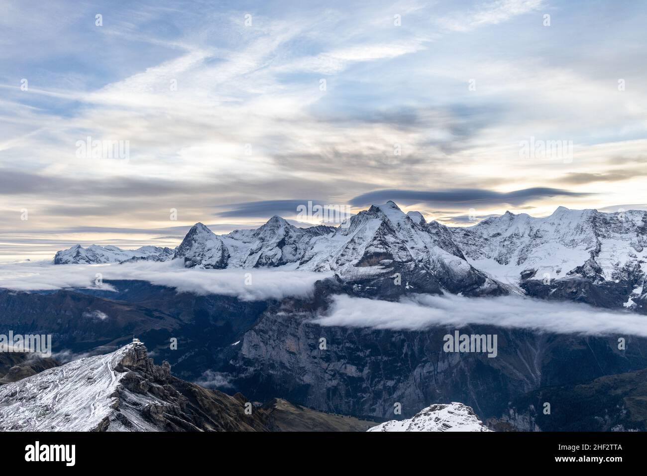 Vista delle famose vette Jungfrau, Mönch ed Eiger dalla montagna Schilthorn nelle Alpi svizzere in Svizzera all'alba con le nubi e la neve drammatiche Foto Stock