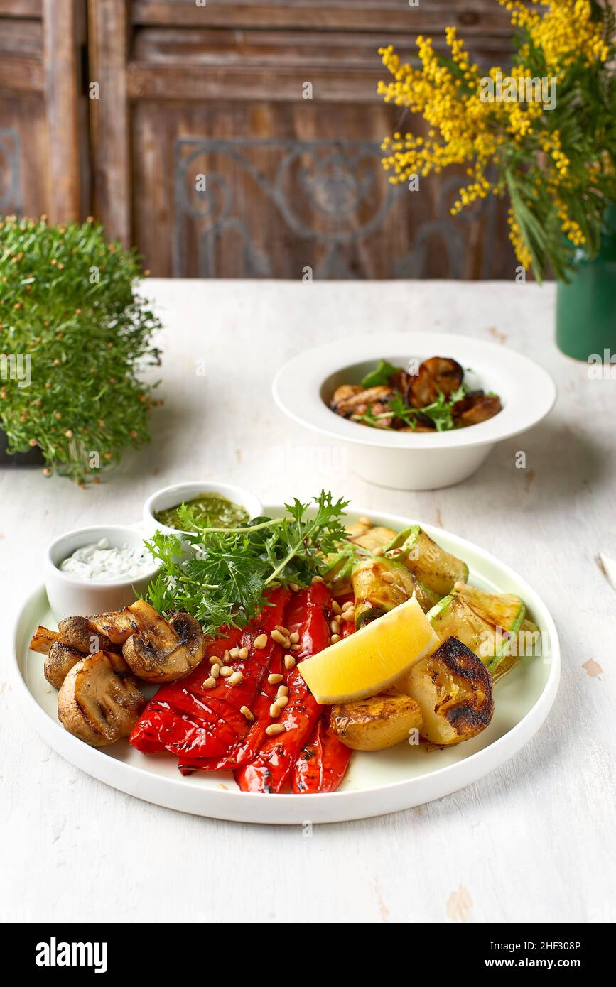 Verdure grigliate melanzane, zucchine, insalata di pepe con salsa di yogurt greco tzadziki su sfondo chiaro, vista dall'alto. Delizioso antipasto, tapas, snac Foto Stock