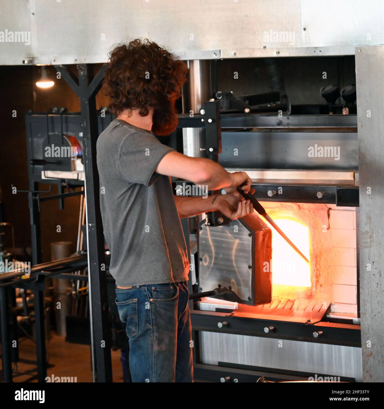 Il personale riscalda il vetro in un forno presso la Lexington Glassworks ad Asheville, Carolina del Nord. Foto Stock