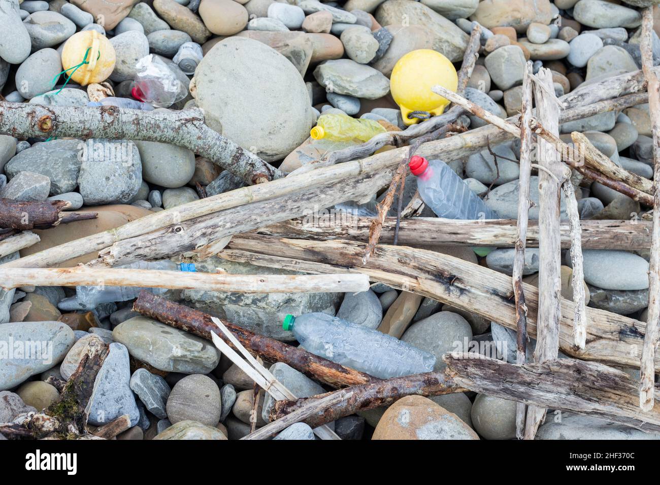 Una spazzatura tra le rocce del mare, bottiglie di plastica, lattine e palle di pescatori. Foto Stock