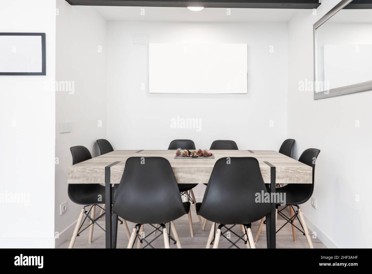 Tavolo da pranzo moderno ed estetico con otto sedie per i commensali in una sala grigia Foto Stock
