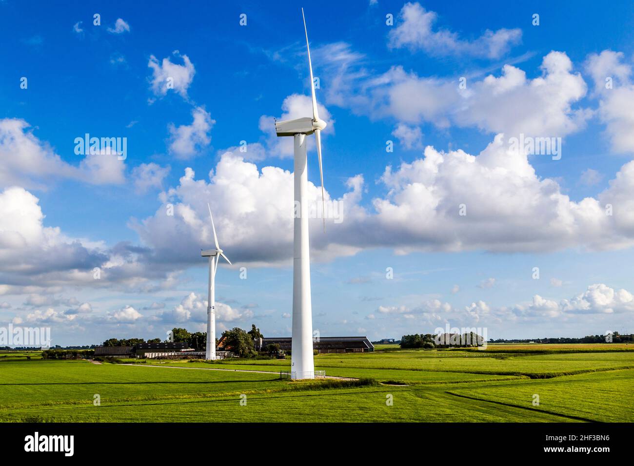Verde prato con turbine eoliche che generano elettricità Foto Stock