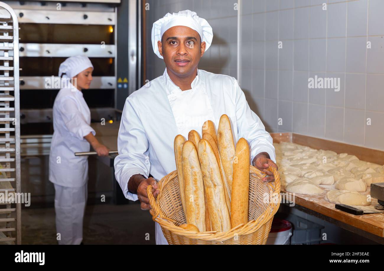 Panettiere ispanico che mostra baguette appena sfornate in panetteria Foto Stock