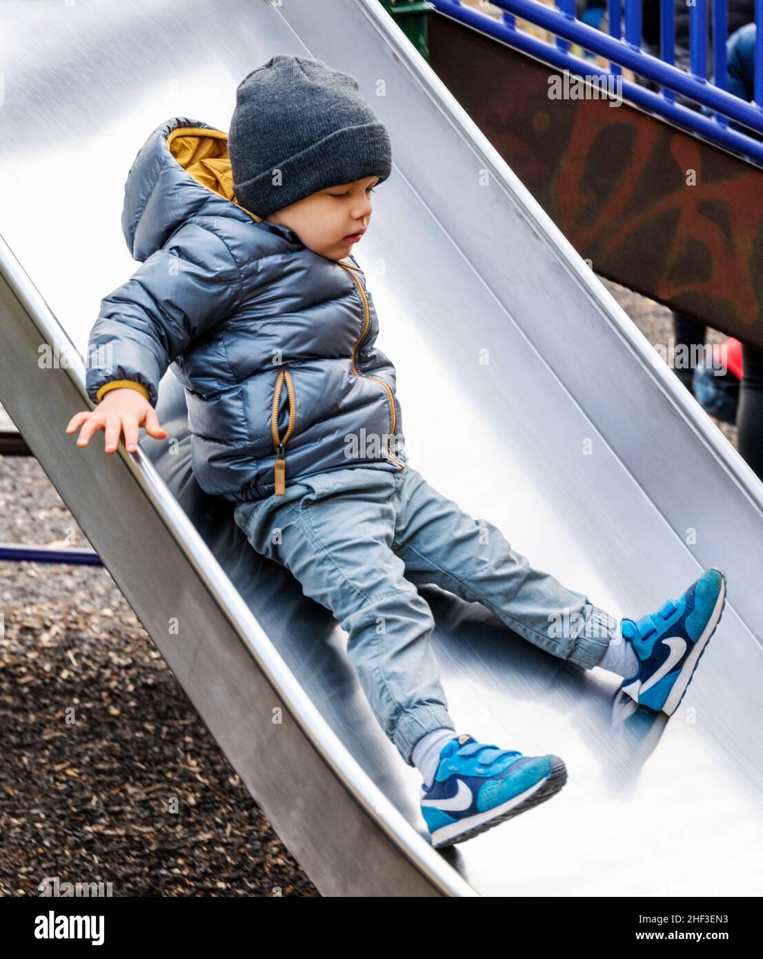 Ragazzo di due anni sul parco giochi della città slidboard Foto Stock