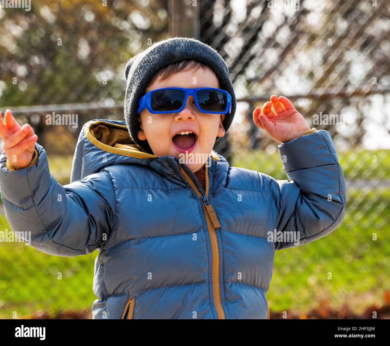 Ragazzo di due anni con occhiali da sole in esecuzione sul parco giochi della città; Corinthian Gardens; Philadelphia; Pennsylvania; USA Foto Stock