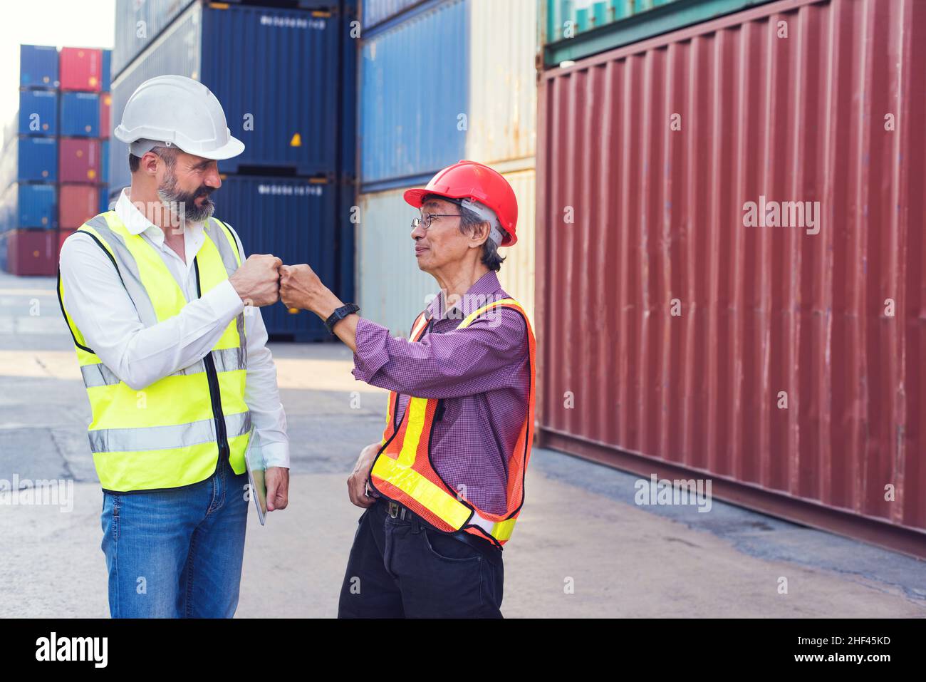 Il caposquadra ed il businessman uniscono le mani al successo di lavoro caricando la scatola dei contenitori dalla nave di trasporto del carico per l'esportazione di importazione. Container per il trasporto in mare. Foto Stock
