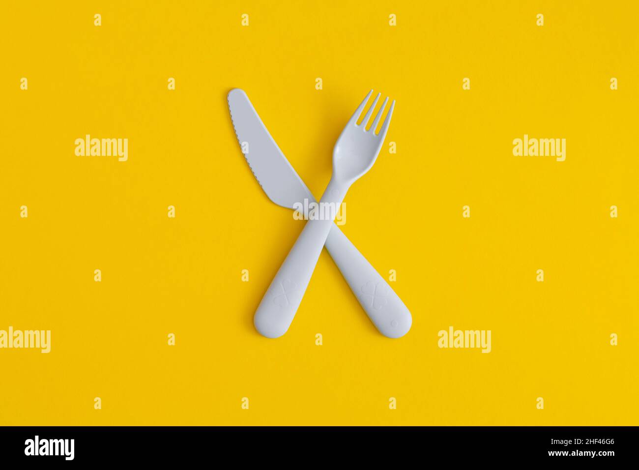 Posate in plastica per alimenti su sfondo giallo. Concetto di riciclaggio di plastica ed ecologia. Foto Stock