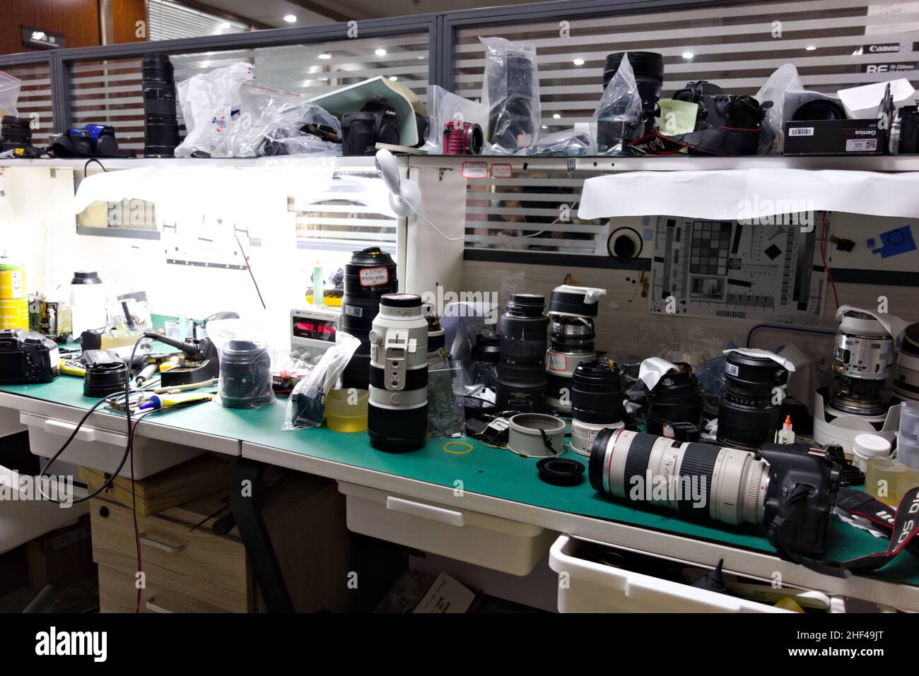 Stazione di lavoro per la riparazione di telecamere e obiettivi con apparecchiature e strumenti Foto Stock