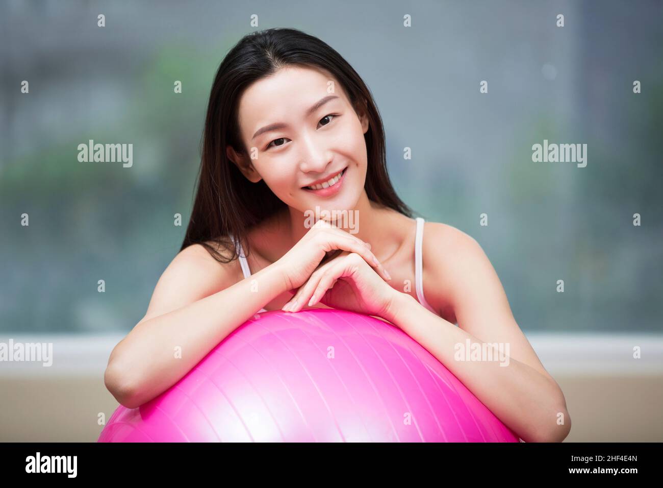 Giovane donna che riposa contro la palla fitness Foto Stock