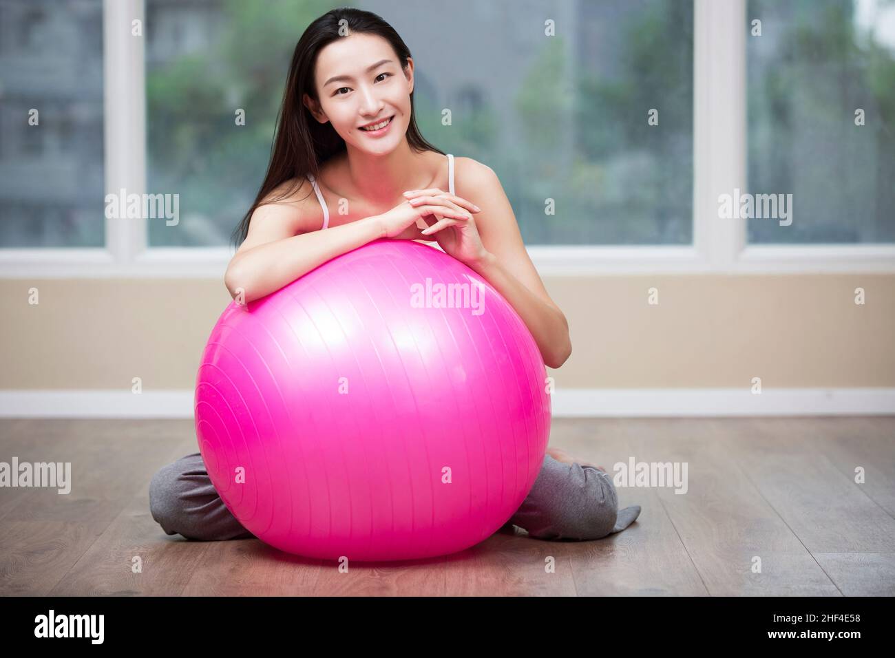 Giovane donna che riposa contro la palla fitness Foto Stock