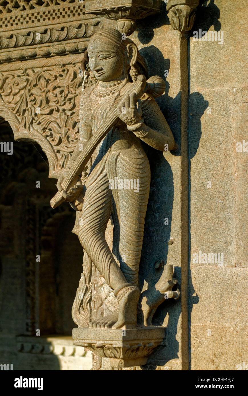 Donna che suona strumento musicale veena scolpito in pietra sul muro del tempio Maheshwar Foto Stock