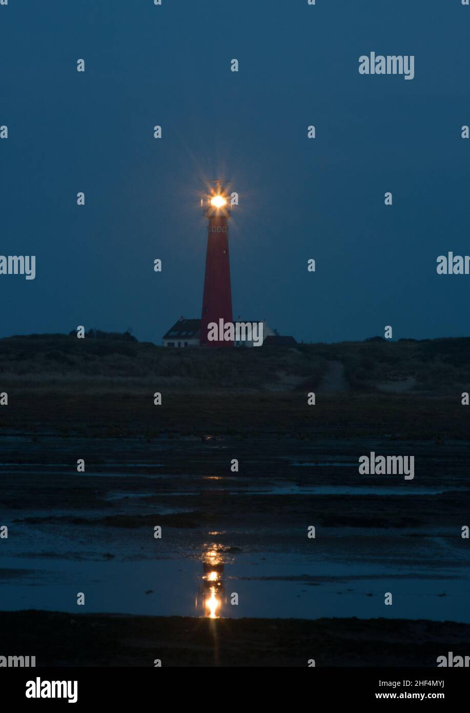 Vista sulla spiaggia di notte sul faro dell'isola olandese di Schiermonnikoog, accanto alla casa bianca del guardiano del faro Foto Stock