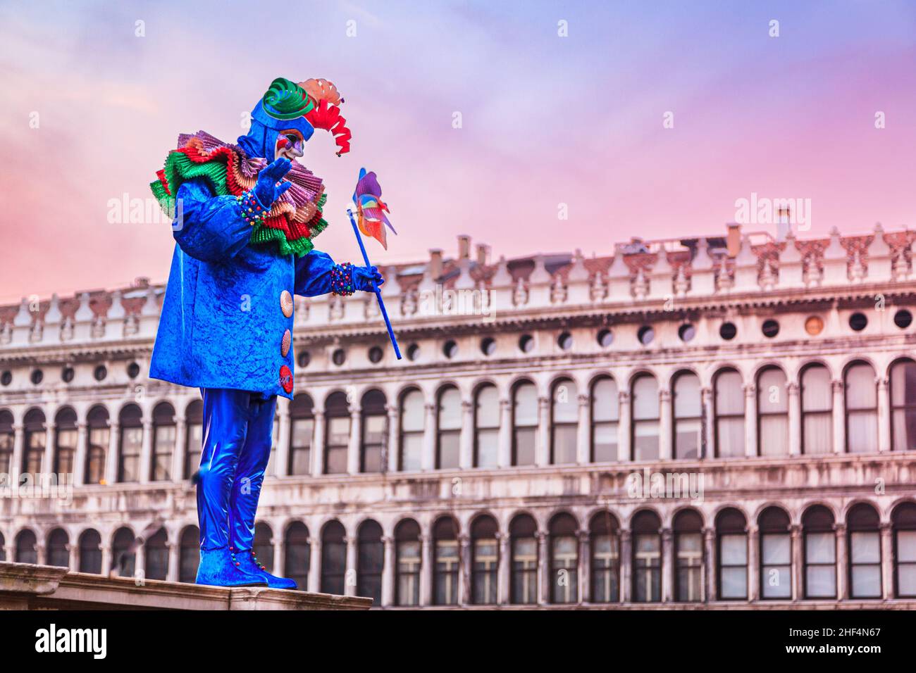 Uomo in posa in coloratissimo costume arlecchino harlequin in Piazza San Marco, Carnevale di Venezia, Carnevale di Venezia, Italia Foto Stock