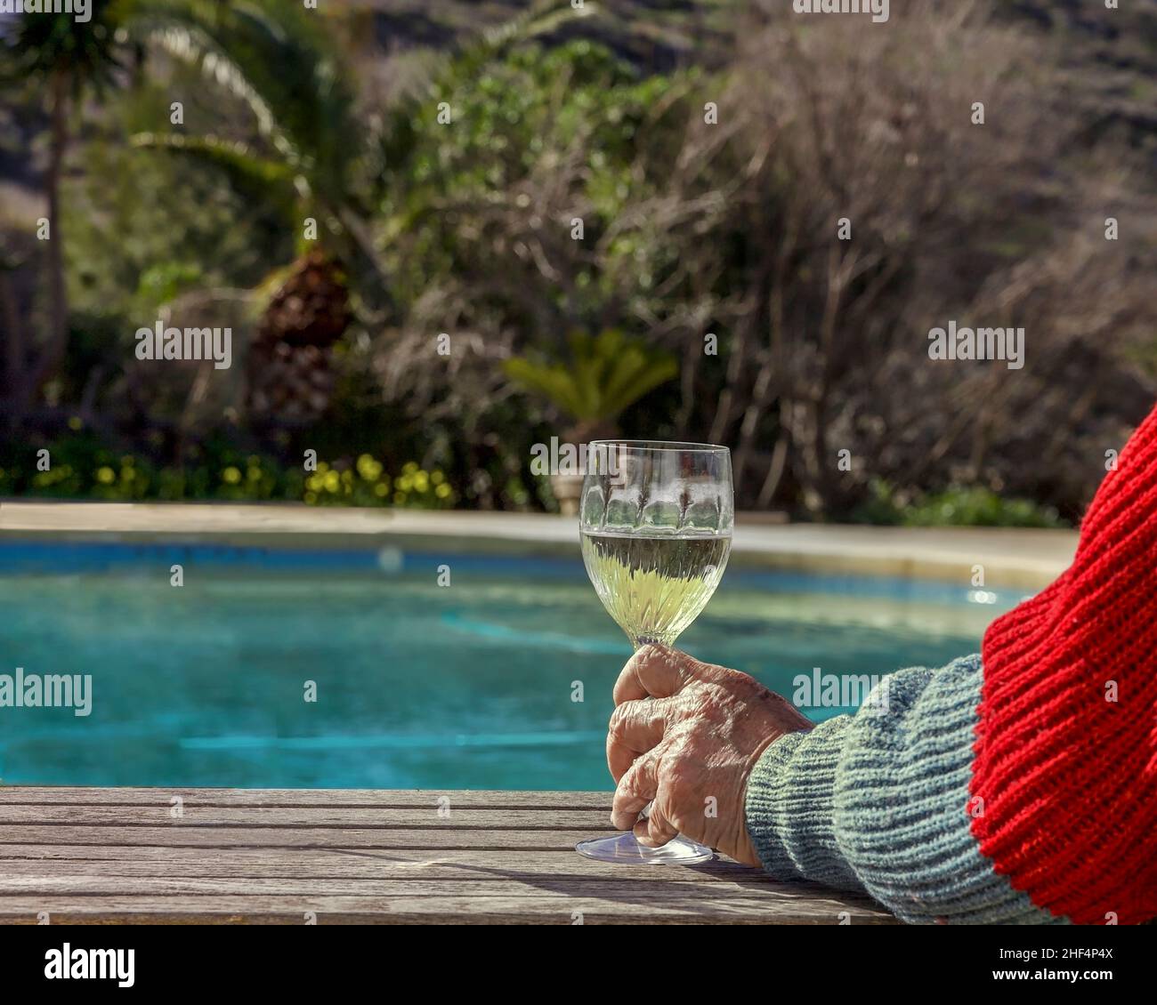 Mani che tengono un bicchiere di vino bianco presso la piscina. Messa a fuoco davanti. Immagine stock. Foto Stock
