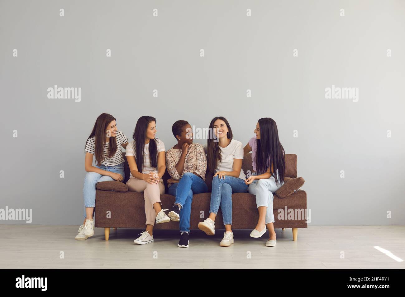 Gruppo di giovani donne felici che trascorrono il tempo libero insieme, seduti sul divano e parlando Foto Stock