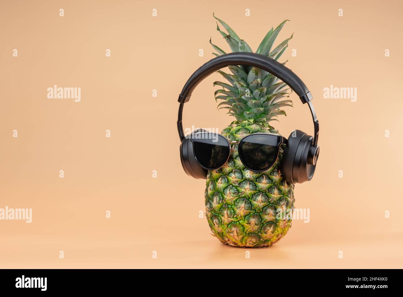 Idea creativa di un'immagine di ananas di una persona cuffie e occhiali come un turista rilassante in vacanza. Su sfondo giallo. Foto Stock