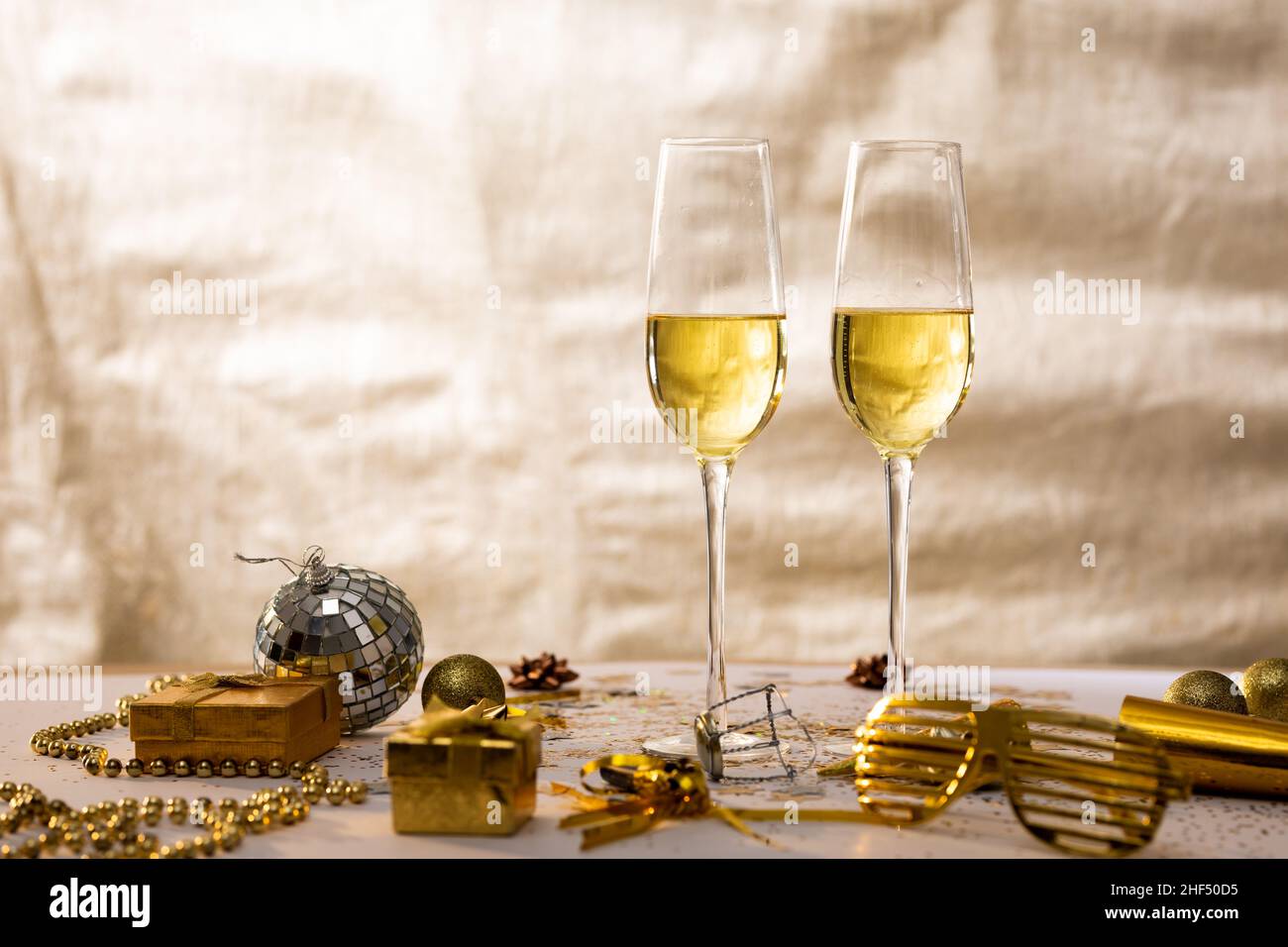 Flute di champagne con decorazione e scatole regalo su sfondo beige, spazio copia Foto Stock