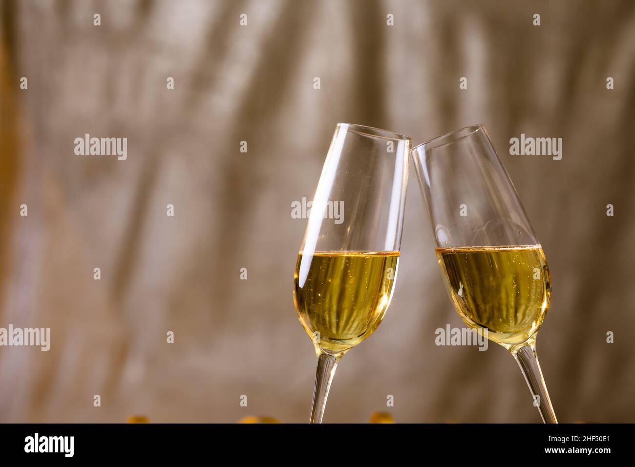 Due flute di champagne che tostano su sfondo beige, spazio copia Foto Stock