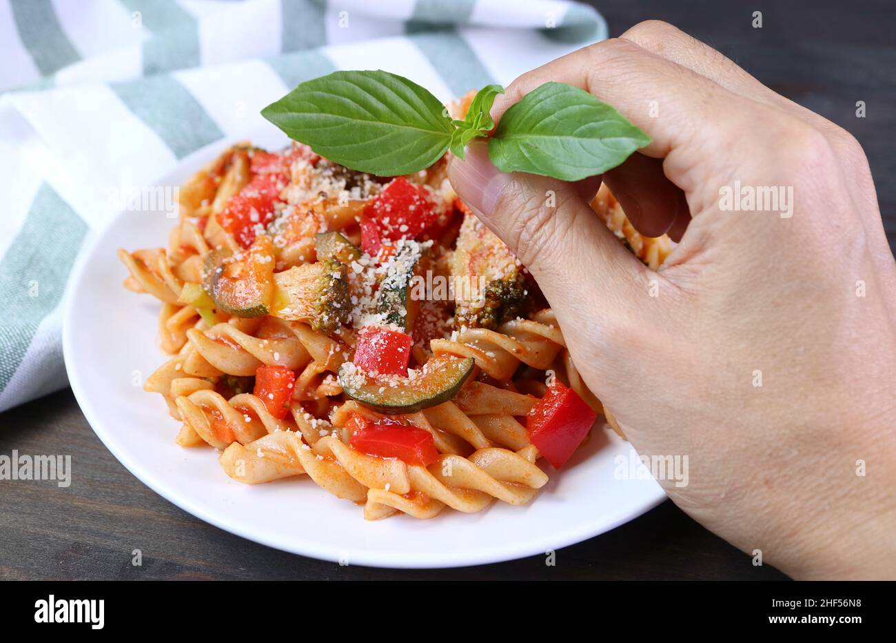 Mettere a mano le foglie di basilico su un piatto di farina di grano fresco cotto Fusilli Pasta in salsa di pomodoro Foto Stock
