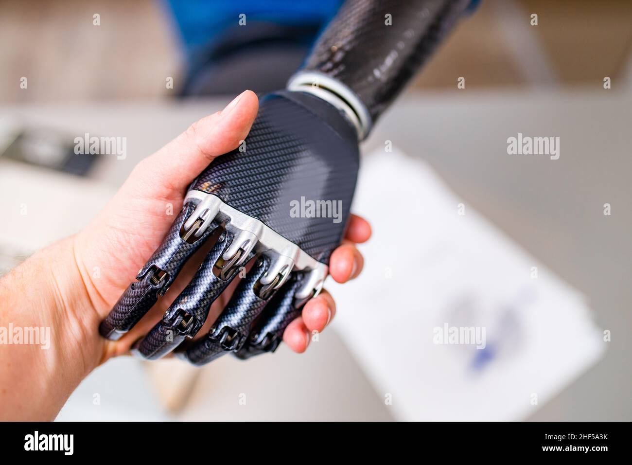 Handshake tra mano umana e mano robot isolato su sfondo ufficio Foto Stock