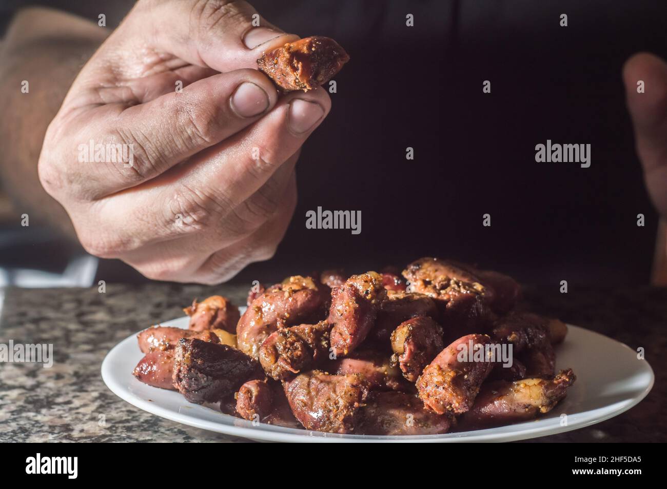 Cuore di pollo su un piatto bianco con sfondo scuro, spazio di copia e fuoco selettivo Foto Stock