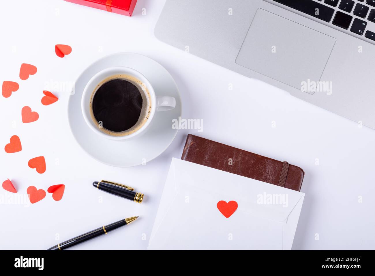 Vista dall'alto del caffè nero con lettera d'amore, penna stilografica, computer portatile su sfondo bianco, spazio copia Foto Stock