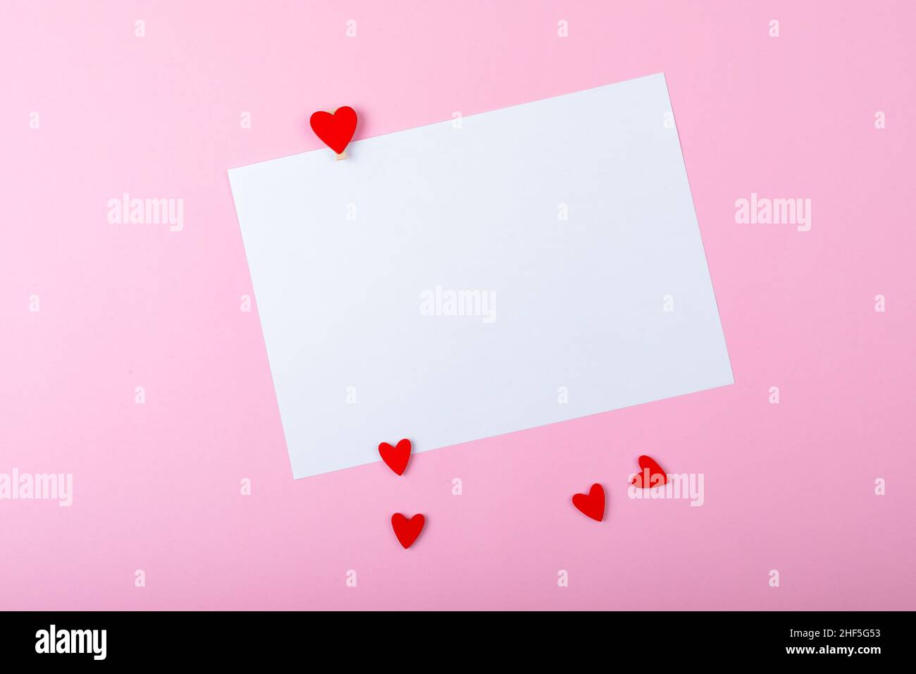 Carta bianca bianca vuota con spazio per la copia piccolo cuore rosso su sfondo rosa Foto Stock