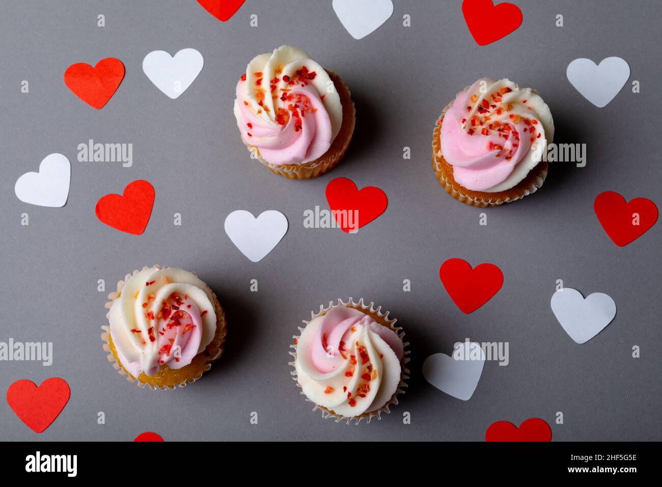 Spruzzatori su cupcake freschi, un cuore bianco e rosso su sfondo grigio Foto Stock