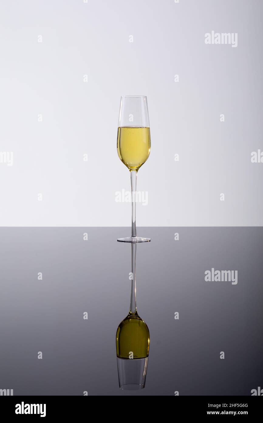 Primo piano di flauto champagne con riflessione sul tavolo di vetro, bere su sfondo bianco Foto Stock