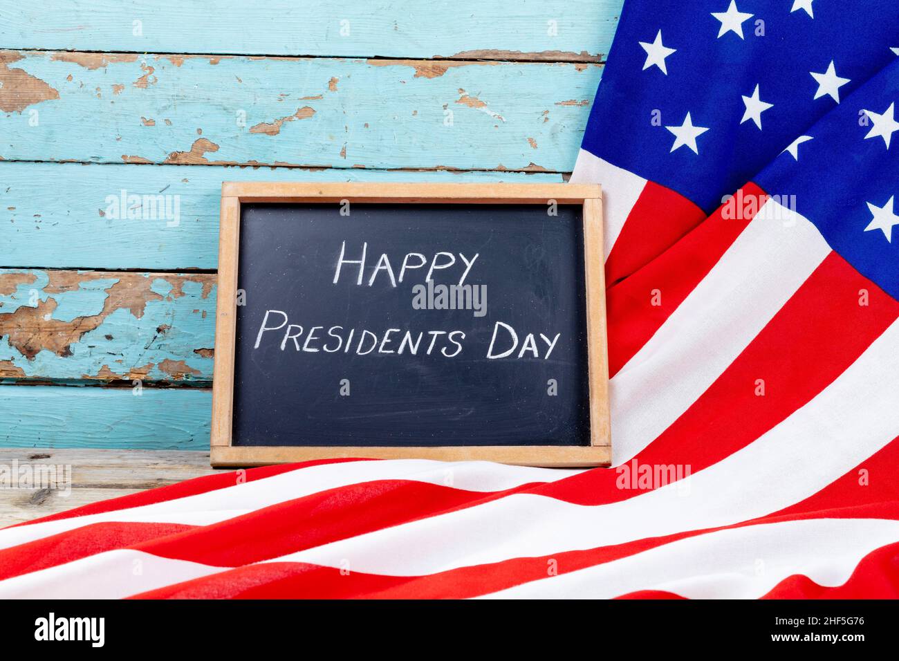Testo del giorno dei presidenti felici sulla scrittura dell'ardesia con la bandiera dell'america sul tavolo blu di legno con lo spazio della copia Foto Stock
