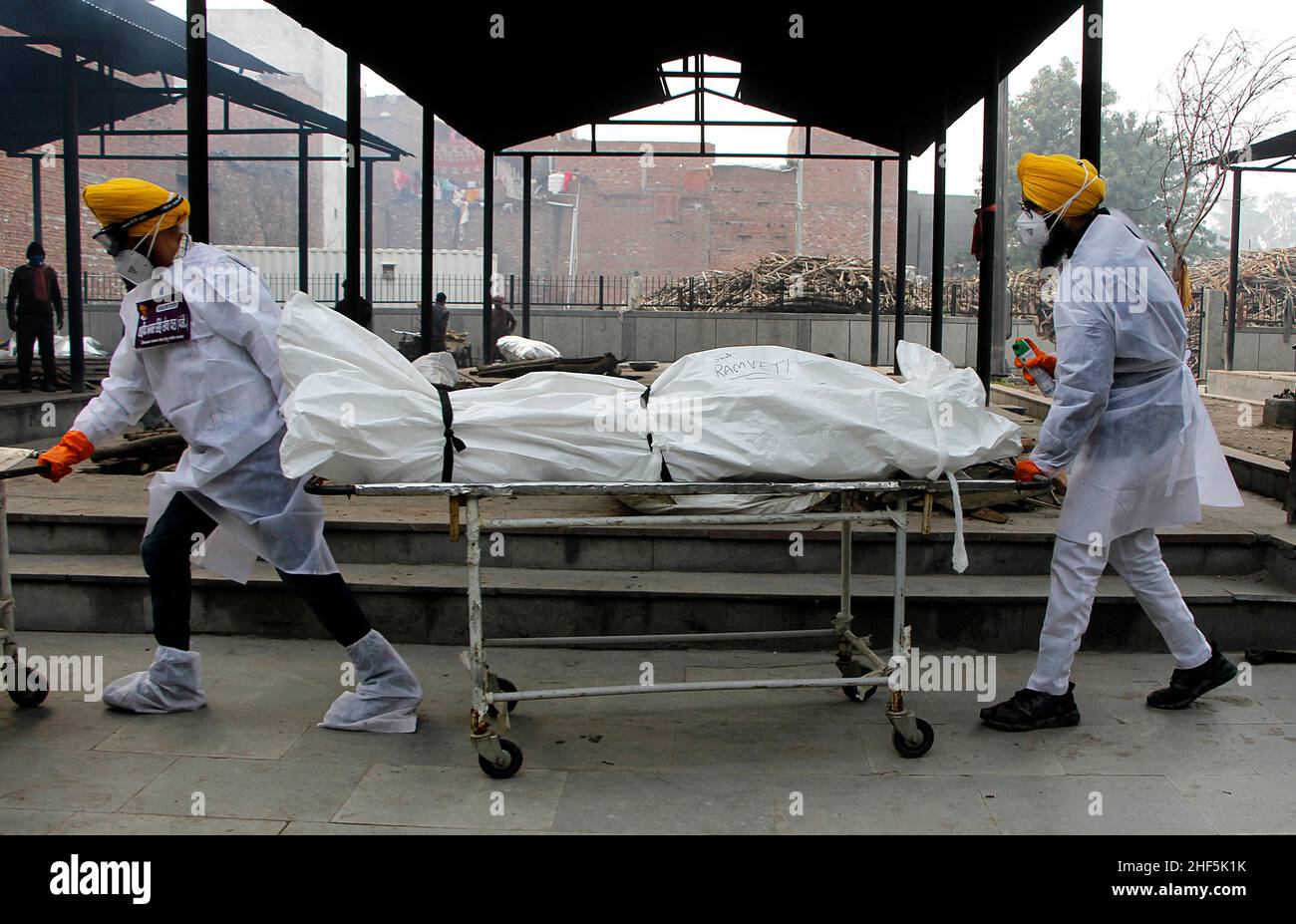 I volontari e i membri della famiglia di una vittima della corona -19 hanno gli ultimi diritti dopo la sua morte in un terreno di cremazione a Nuova Delhi. Foto Stock