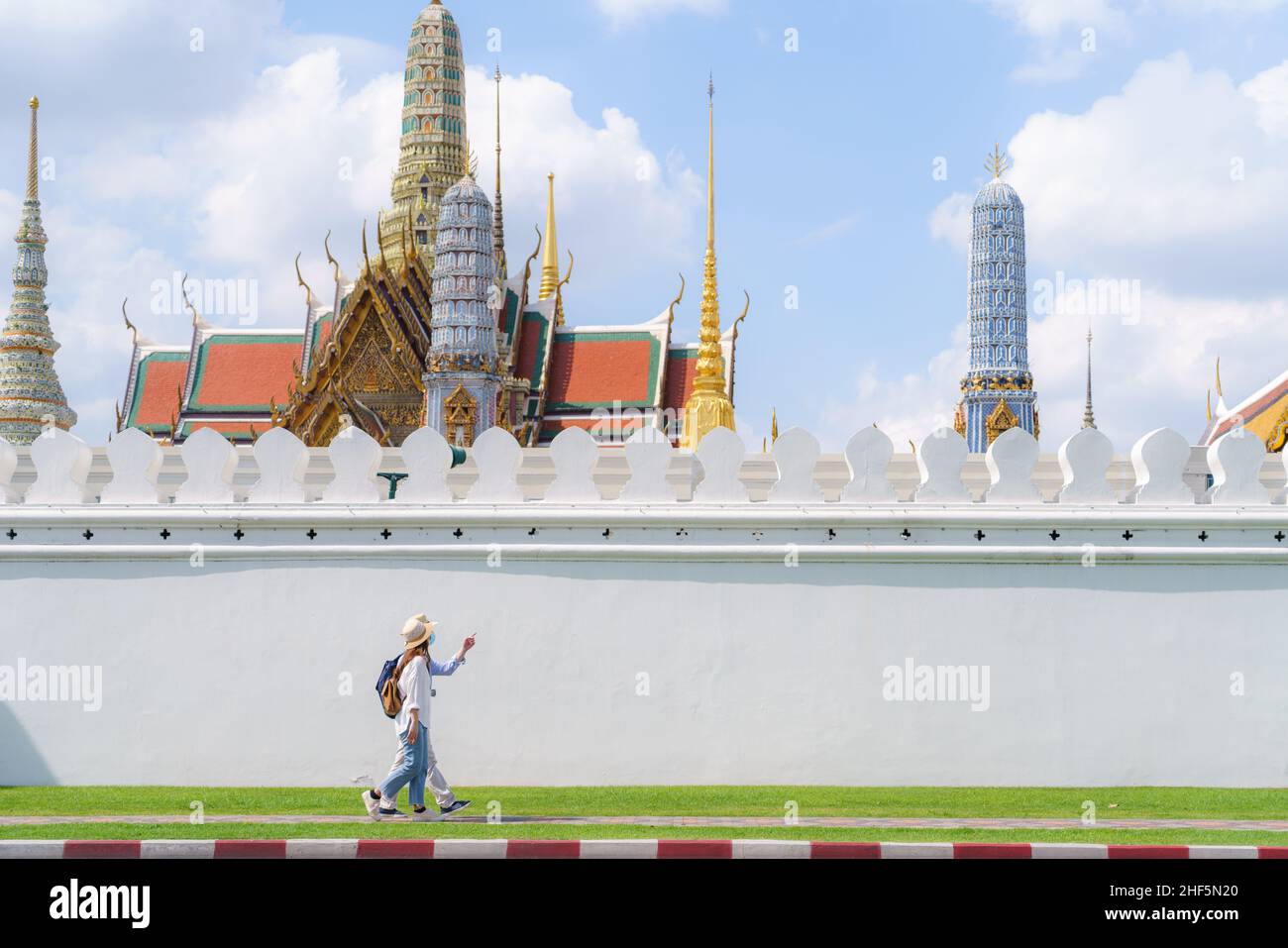 Coppie asiatiche turisti felici di viaggiare indossando maschera per proteggere da Covid-19 in loro vacanze nel tempio Wat Phra Kaew a Bangkok, Thailandia Foto Stock