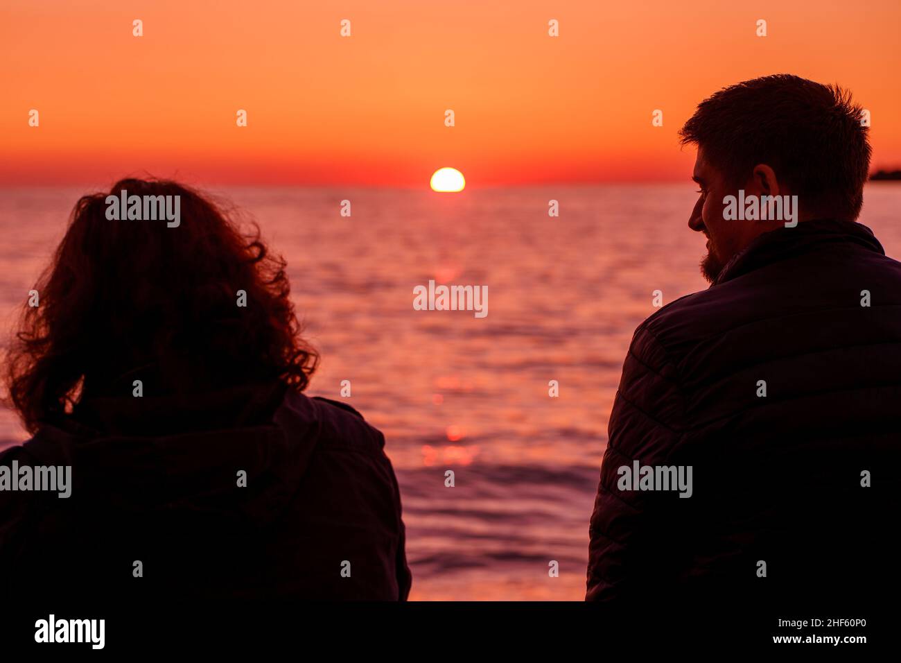 Marito e moglie. Romanticismo. Viaggiatori. Data. Una giornata nella natura. Un uomo e una donna si siedono sulla spiaggia di pietra e godersi il mare d'inverno e la bella o Foto Stock