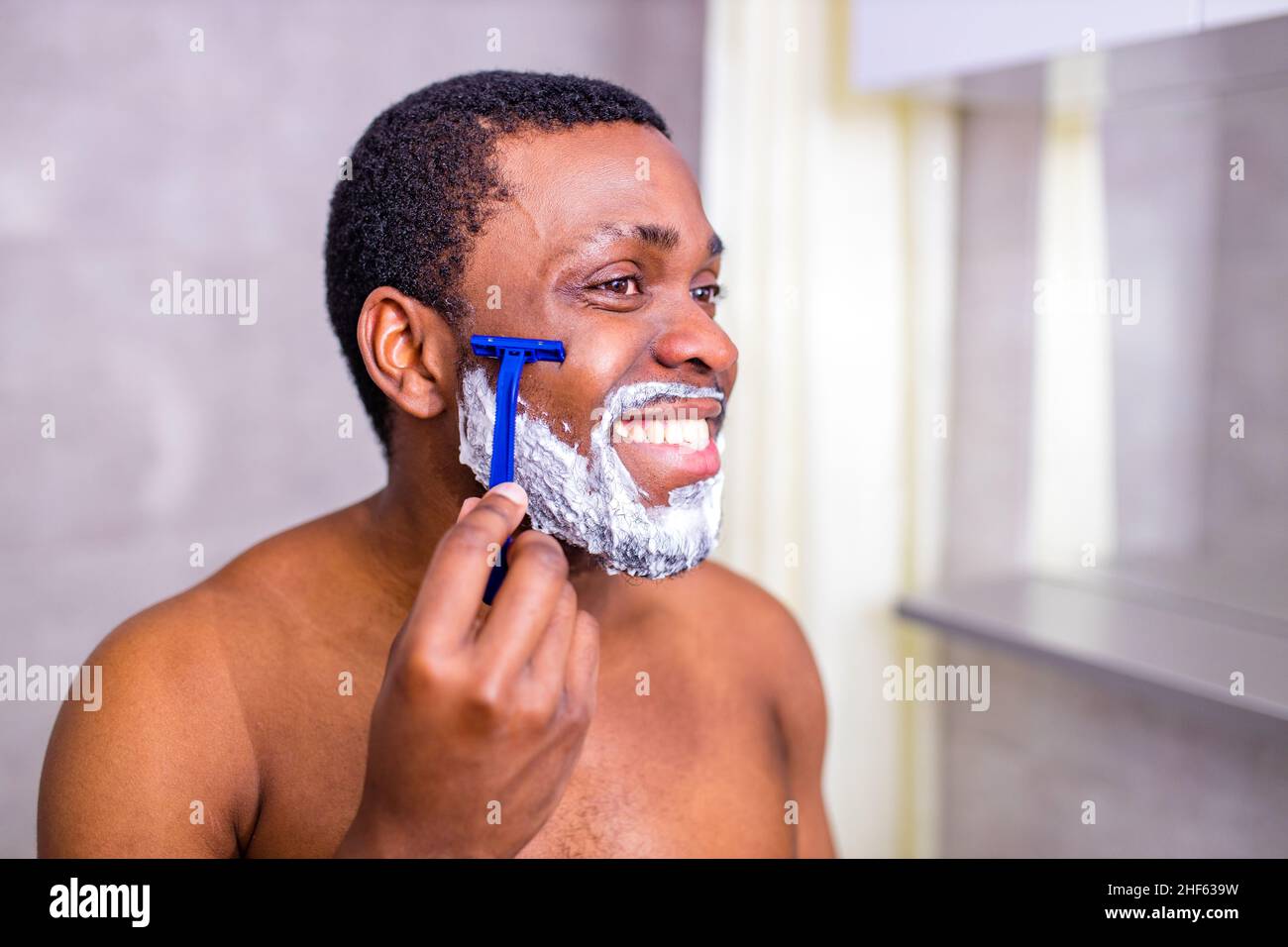 l'uomo ispanico ha messo su schiuma su crema di profumo di barba o crema di cura della pelle per la pelle sensibile Foto Stock