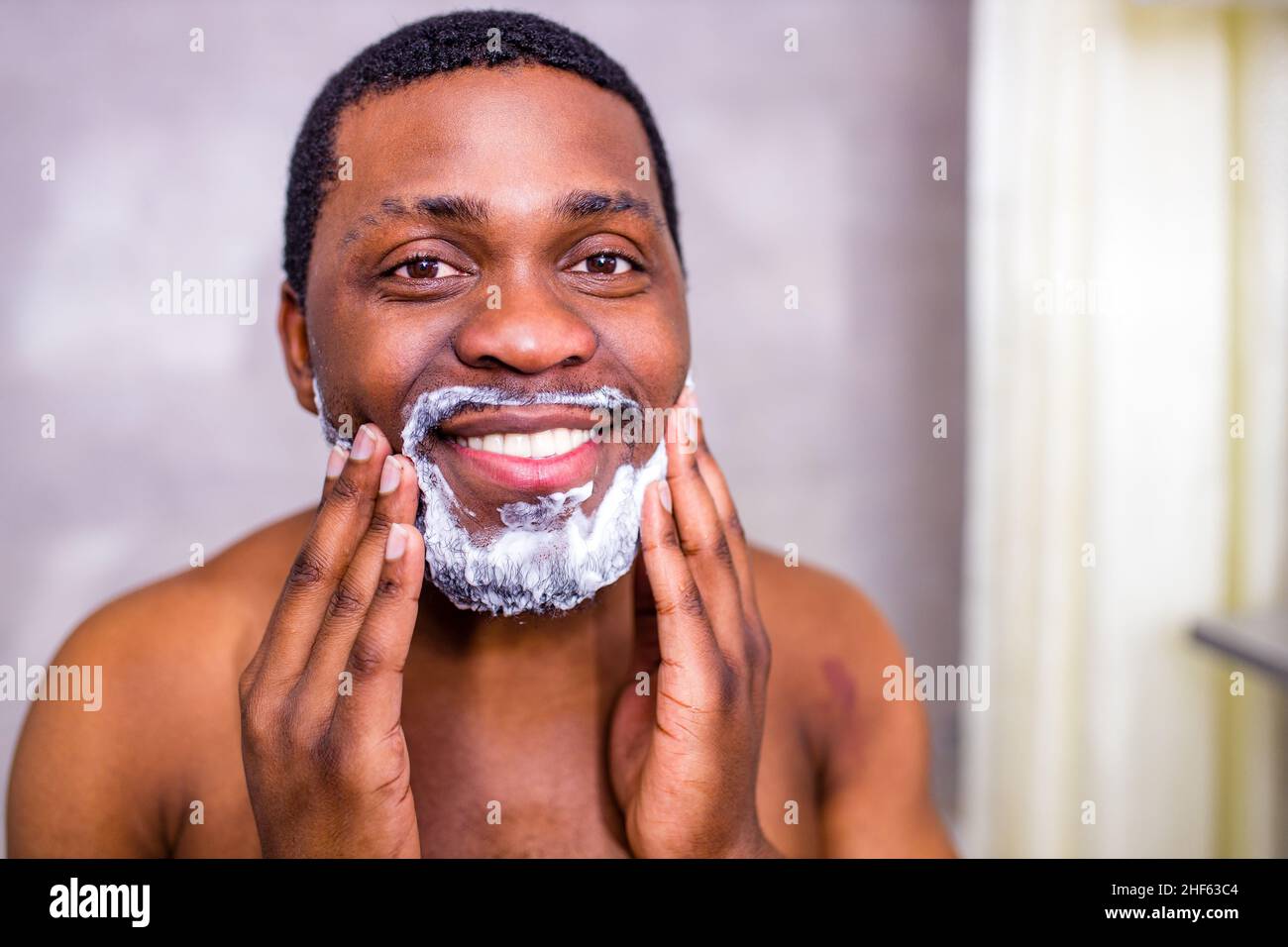 l'uomo ispanico ha messo su schiuma su crema di profumo di barba o crema di cura della pelle per la pelle sensibile Foto Stock