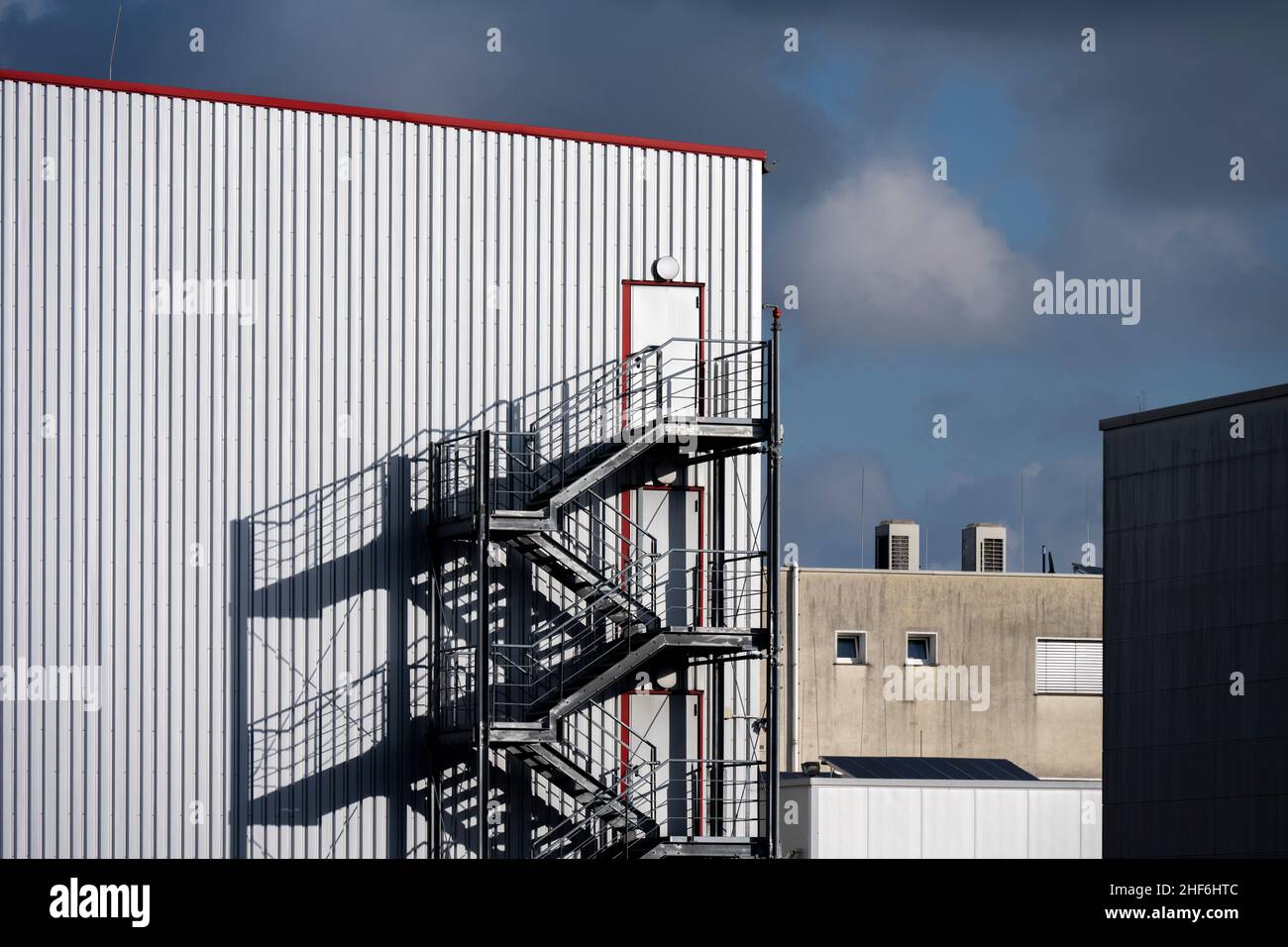 Magazzino, scale esterne, cornici rosse, nuvole, area industriale Foto Stock