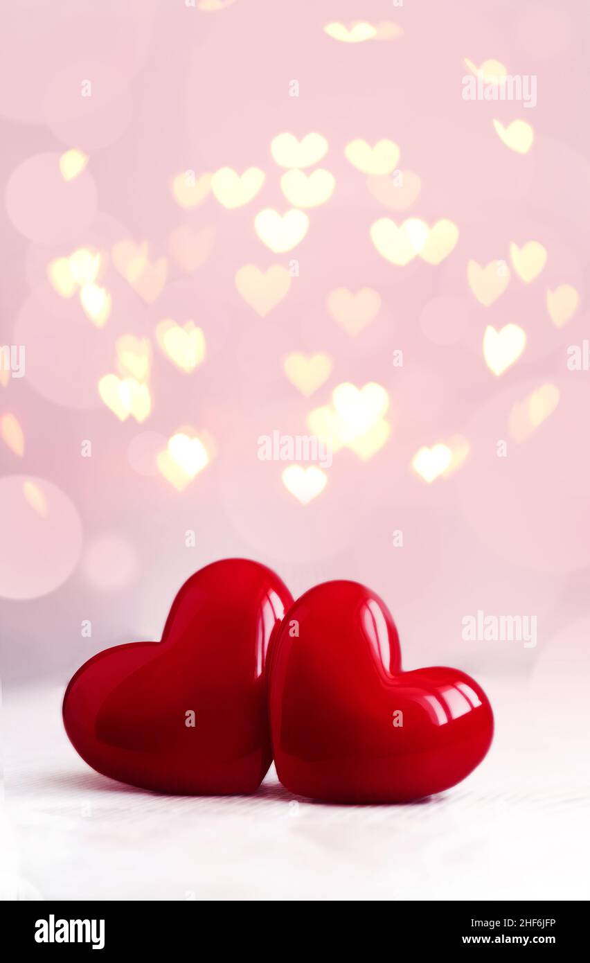 Sfondo del giorno di San Valentino con cuori di plastica lucenti sulla luce. Biglietto giornaliero per gli amanti felici, spazio copia. Foto Stock