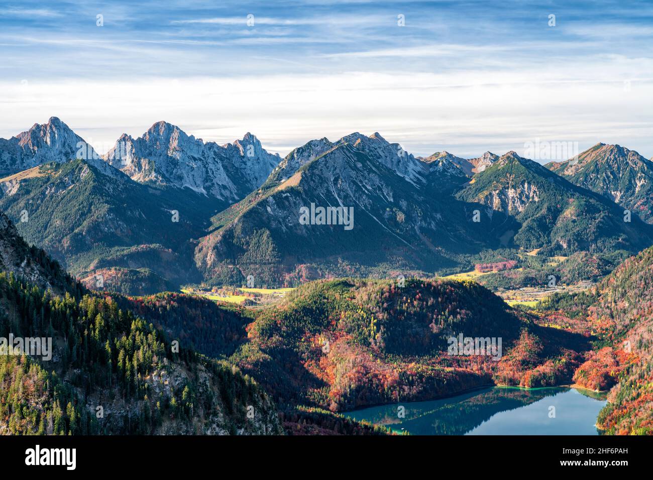 Paesaggio montano selvaggio e romantico con foresta autunnale colorata e montagne rocciose sotto un cielo blu. Alpsee vicino a Füssen. Sullo sfondo le Alpi Allgäu. Baviera, Germania, Europa Foto Stock