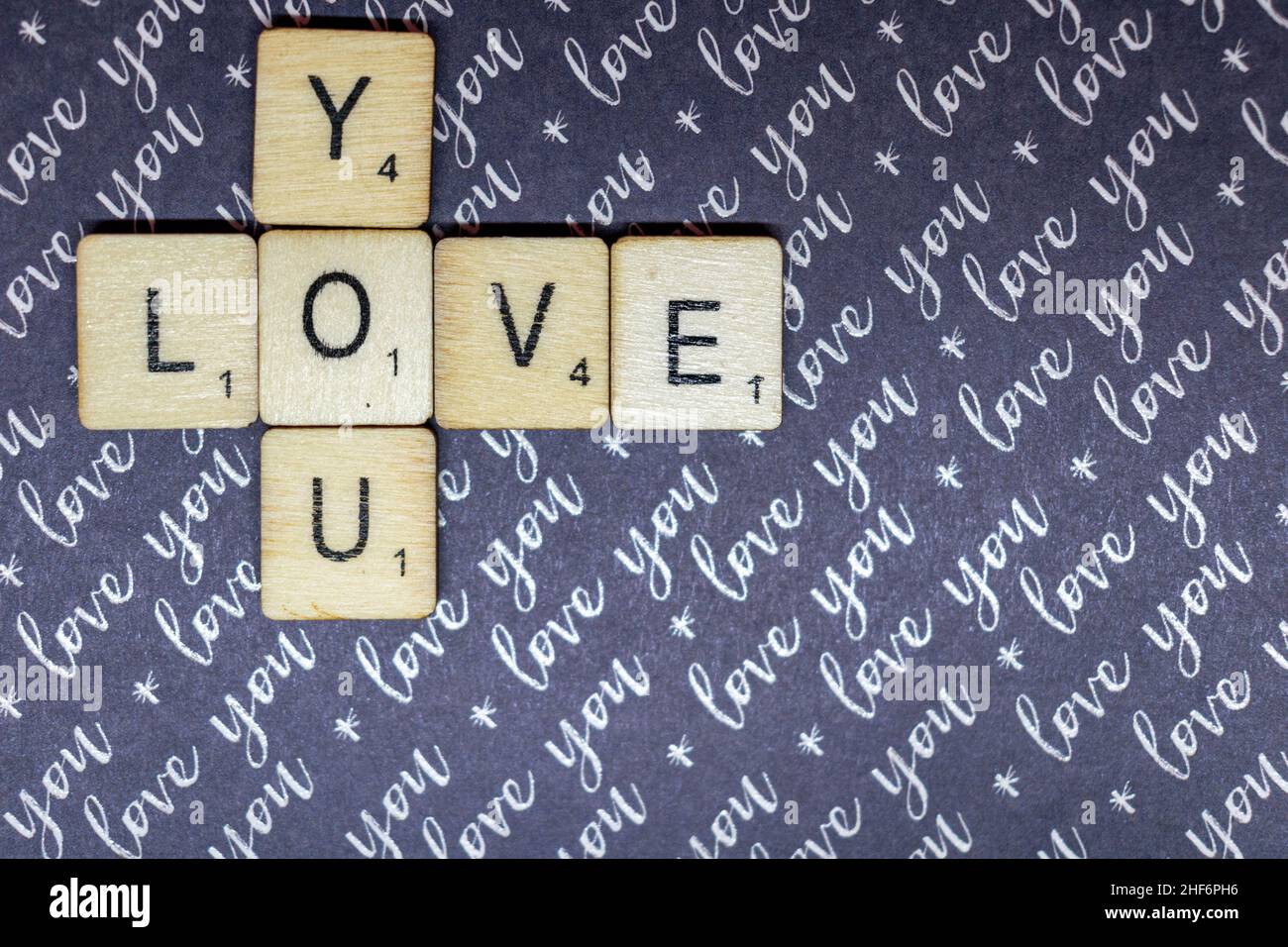 Concetto di amore e romanticismo. Amore che hai scritto su scrabble giocare a cubetti su un viola che ti amo sfondo. Giornata di San Valentino, concetto romantico, compagno Foto Stock