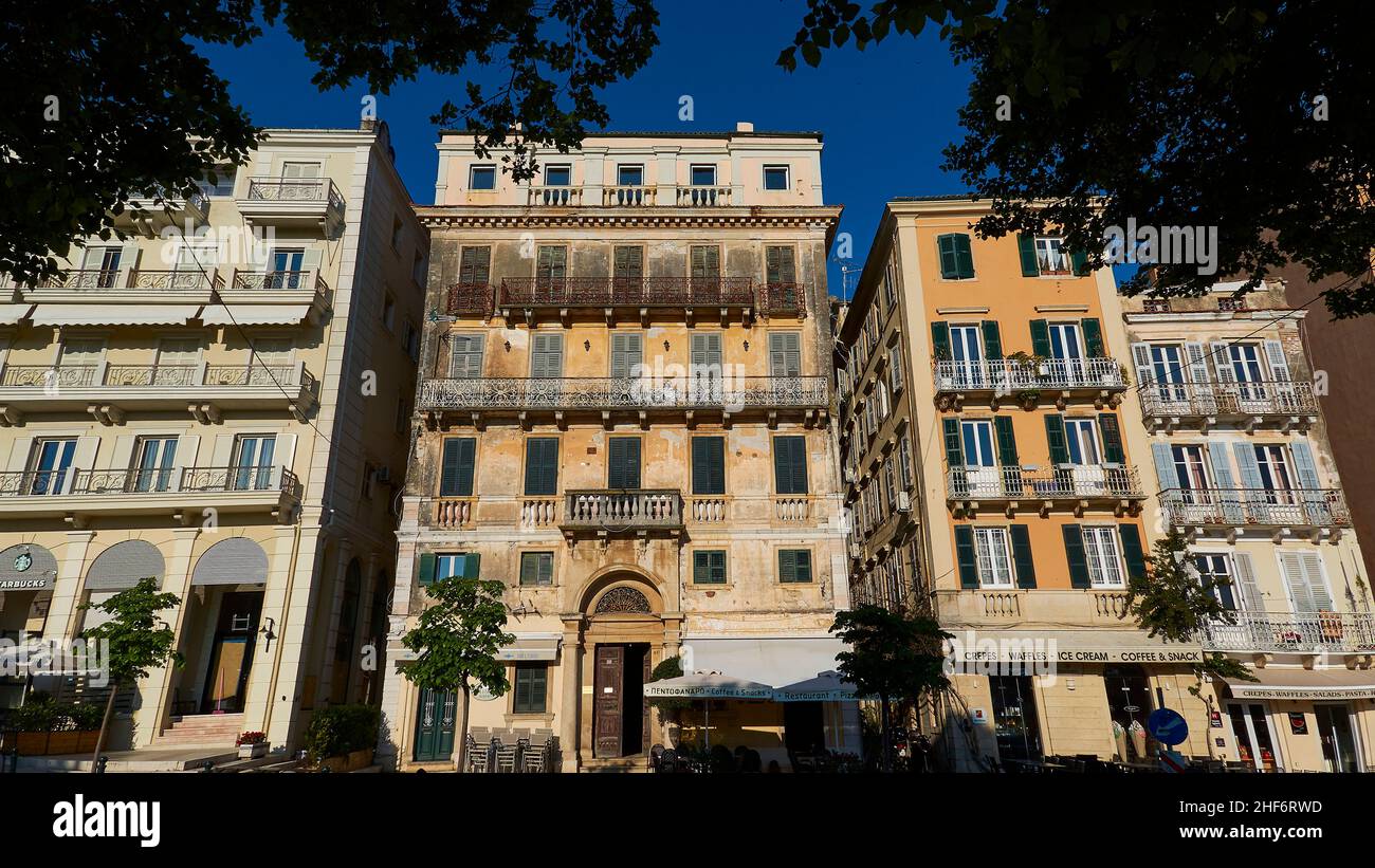 Grecia, Isole greche, Isole IONIE, Corfù, Corfù, Città vecchia, edifici storici ai margini della città vecchia vicino al Liston, ampio angolo di vista obliquamente dal basso, cielo blu, sopra rami e foglie in ombra in primo piano Foto Stock