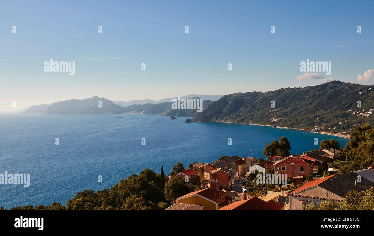 Grecia, Isole greche, Isole IONIE, Corfù, costa occidentale, Pentati, vista di parte di Pentati e il mare blu, verdi colline lungo la costa sullo sfondo Foto Stock