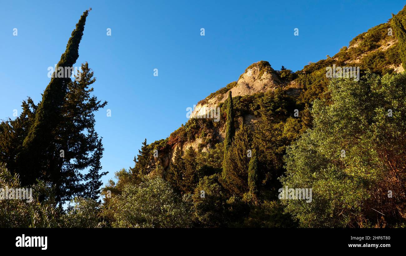 Grecia, Isole greche, Isole IONIE, Corfù, costa occidentale, Pentati, luce del pomeriggio, percorso da Pentati ad Agios Gordios, vista della roccia su un pendio, color ocra, tra cui alberi, cielo blu Foto Stock