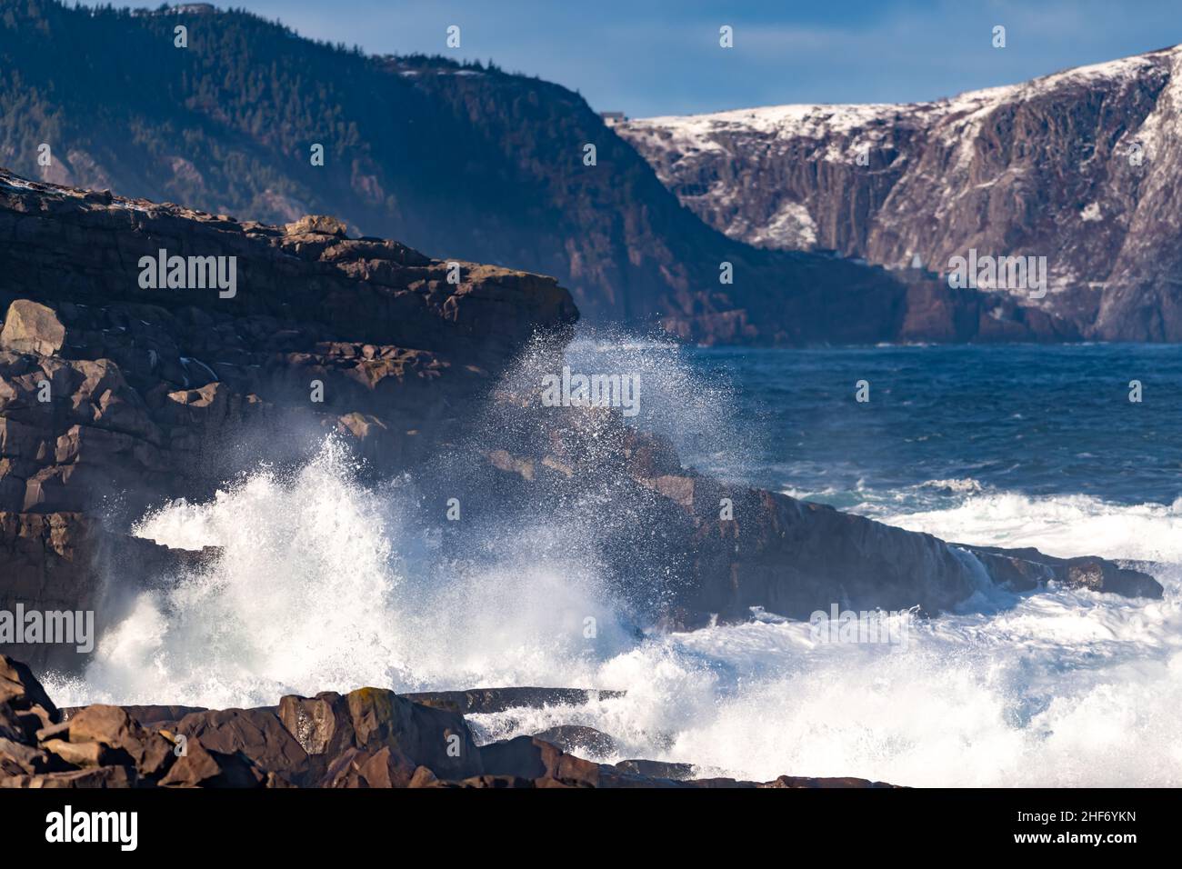 Un arrabbiato colore verde turchese massiccio arricciatura di un'onda come rotola lungo una spiaggia. La nebbia bianca e la schiuma dell'onda sono schiumose e soffici. Foto Stock