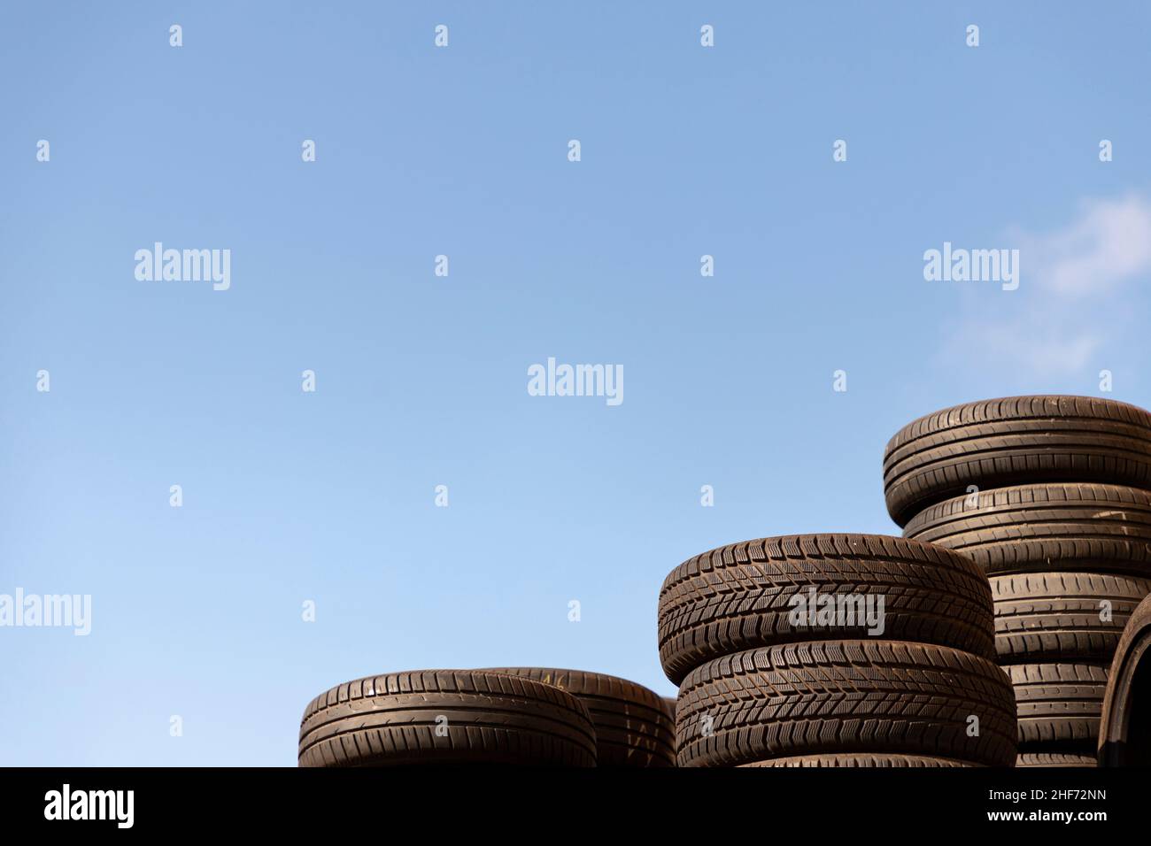 rifiuti impilati vecchi pneumatici contro il cielo blu Foto Stock