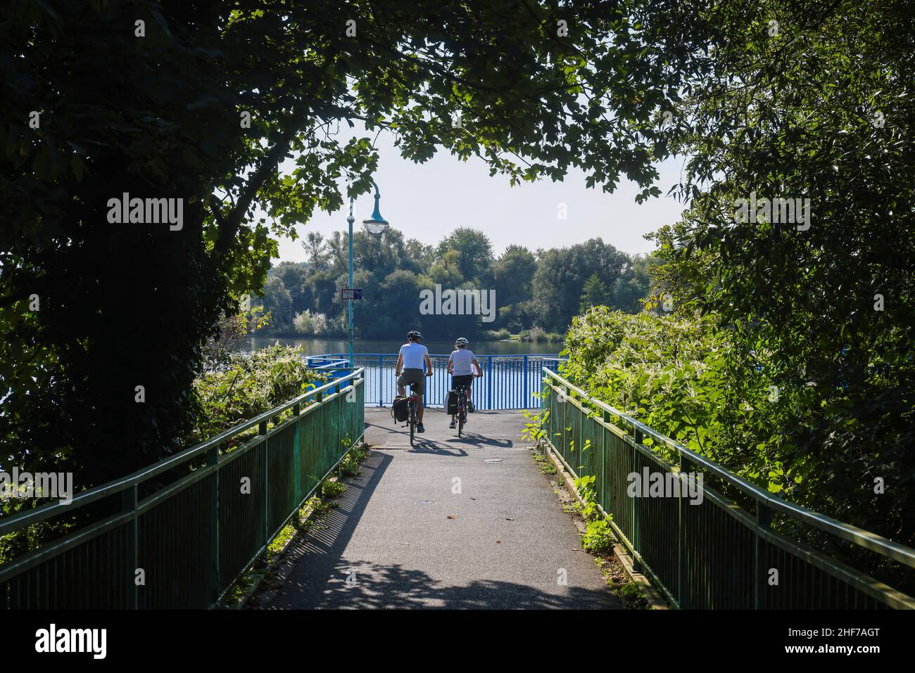 Muelheim an der Ruhr, Renania settentrionale-Vestfalia, Germania - Saarn-Mendener Ruhraue, zona verde della Ruhr. I ciclisti cavalcano sul sentiero e sulla pista ciclabile del Ruhrinsel sopra lo stramazzo Muelheim an der Ruhr. Foto Stock