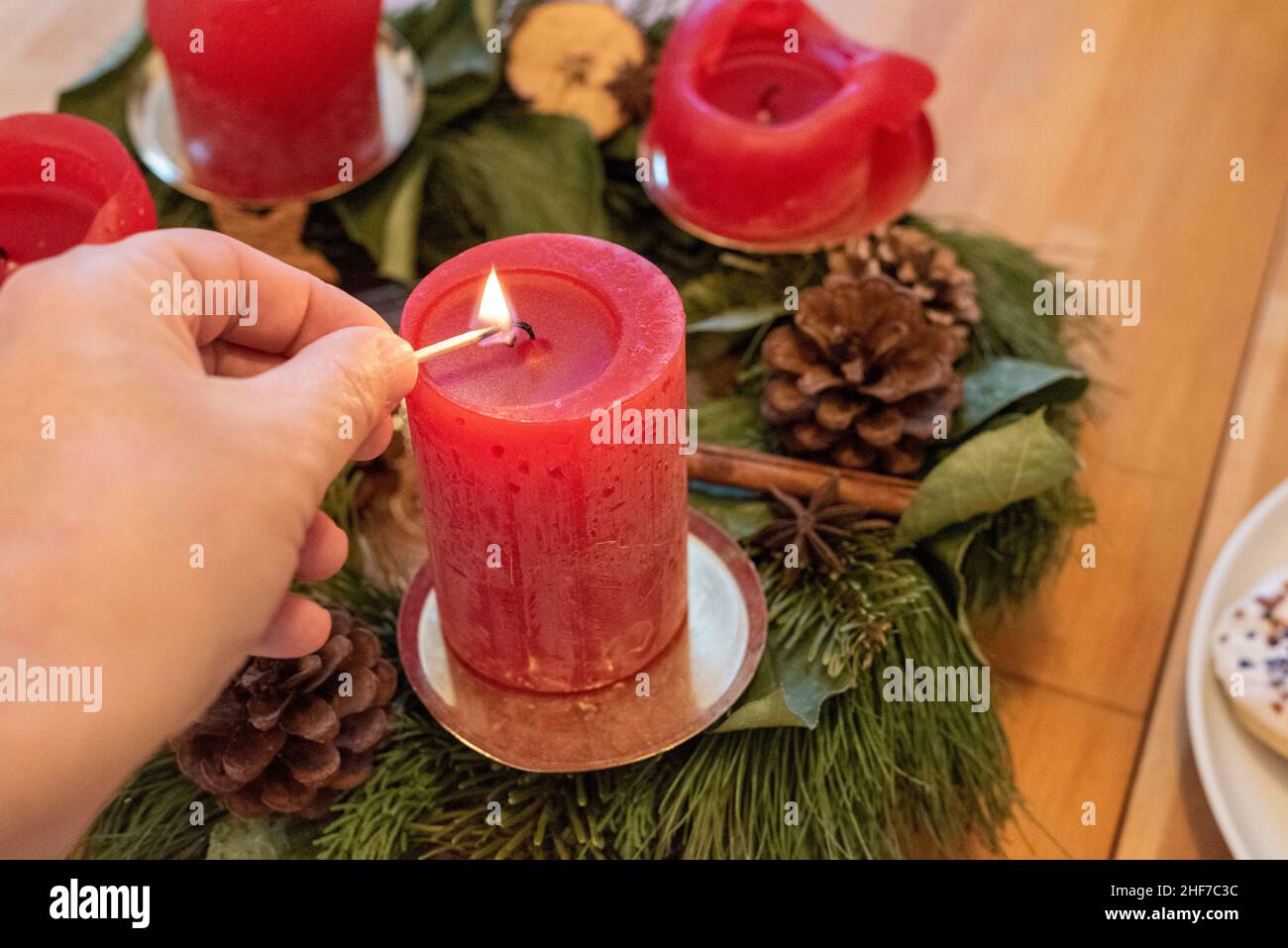 La mano maschile accende una candela d'avvento. Foto Stock