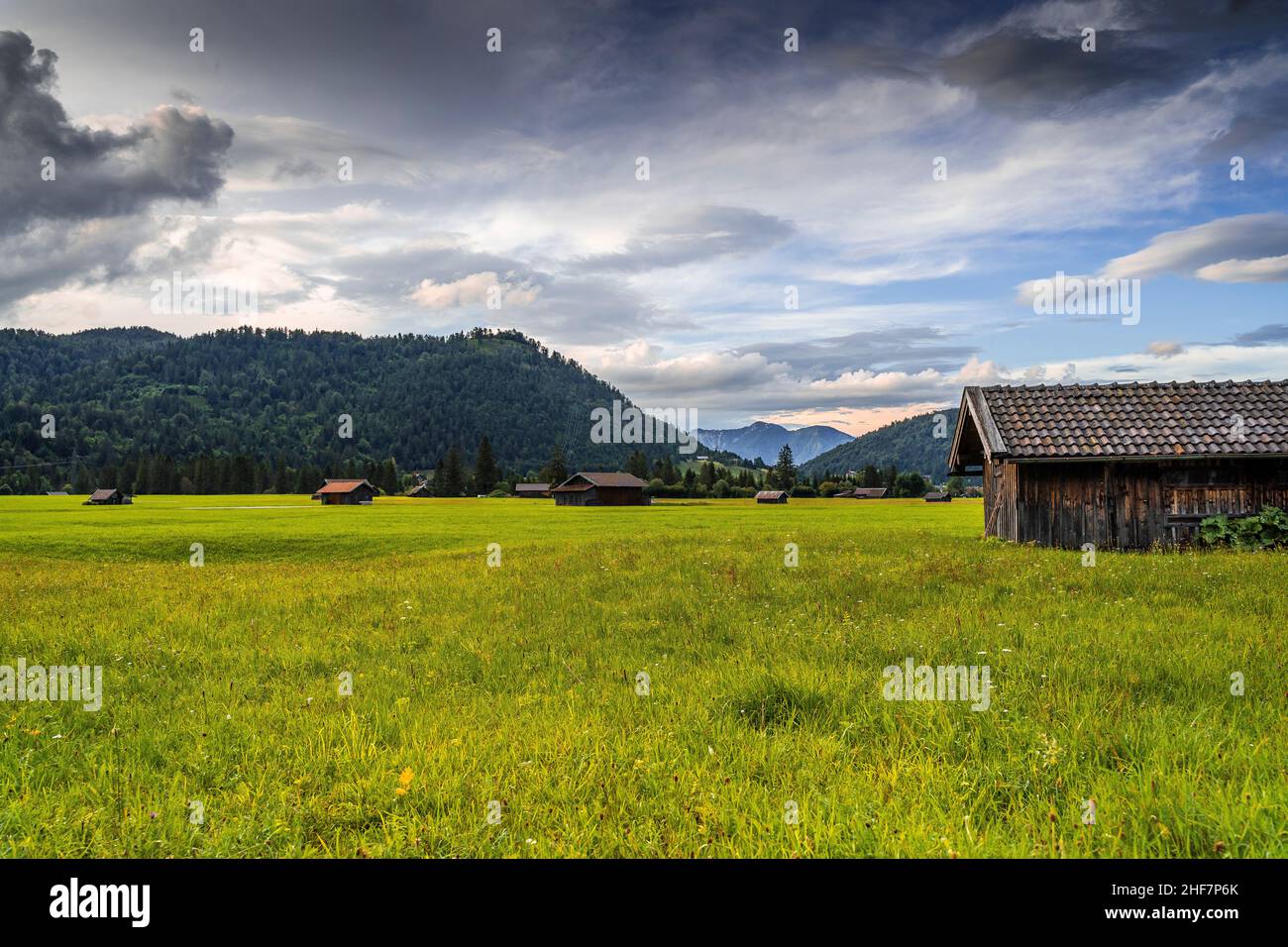 Vista a Wallgau con Krepelschrofen, dietro di esso il Herzogstand, in primo piano diversi fienili su prati verdi, Baviera, Germania Foto Stock