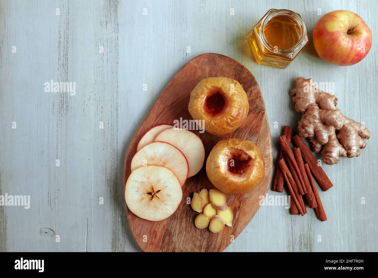 Mela al forno con miele, cannella e zenzero su un tavolo di legno chiaro Foto Stock
