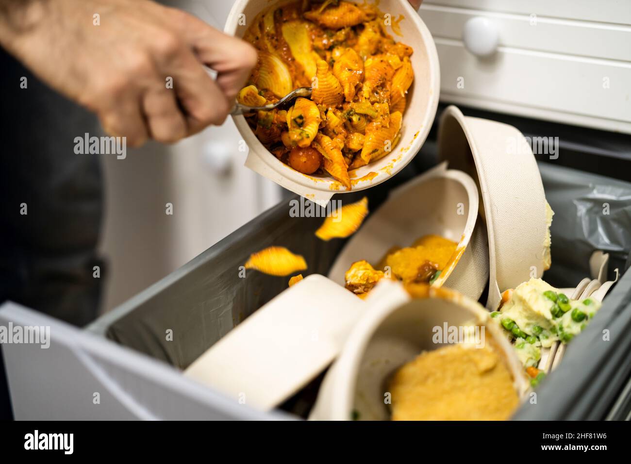 Gettando via cibo residuo nel cestino o nel cestino della spazzatura Foto Stock